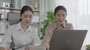 Ofis çalışma alanında birlikte çalışan iki genç hevesli iş kadını. Genç meslektaşlar tartışırken ve dizüstü bilgisayar kullanırken. Modern ofis çalışanları masada birlikte oturuyorlar..