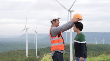 Oğluyla birlikte kırsal kesimdeki bir tepenin tepesinde ya da dağda bir rüzgar çiftliğinde mühendis. Yenilenebilir ve sürdürülebilir enerjinin gelecekteki üretimi için yenilikçi bir ideal. Rüzgar türbininden enerji üretimi.
