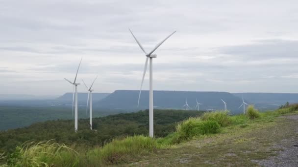 グリーンフィールドや丘の上に風力タービンファームによって現代の生活様式を電力する再生可能エネルギー源として風力を利用する進歩的な方法 風車発電機はCo2排出のない電気を発生させます — ストック動画