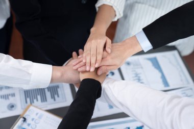 Top view closeup business team of suit-clad businesspeople join hand stack together. Colleague collaborate and work together to promote harmony and teamwork concept in office workplace.