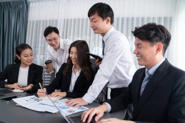 Harmony in office concept as business people analyzing dashboard paper together in workplace. Young colleagues give ideas at manager desk for discussion or strategy planning about project.