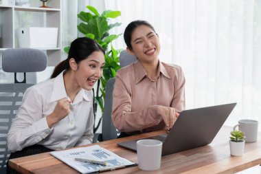 Modern ofis çalışma alanında iş birliği yapan iki genç ofis çalışanı, modern ofis çalışanı olarak profesyonelliklerini sergileyerek, dizüstü bilgisayarda tartışıyorlar ve birlikte çalışıyorlar. Coşkulu.