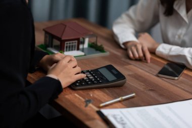 Temsilciyle ev kredisi sözleşmesini gözden geçiriyorum. Mali belgeleri ve vergi oranlarını, mülkiyet sahibi olmak için hesap makinesiyle analiz ediyorum. Yeni ev alımı ve finansman için anahtar imza. Coşkulu.