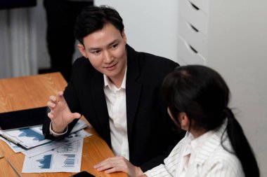 Harmony in office concept as business people analyzing dashboard paper together in workplace. Young colleagues give ideas at manager desk for discussion or strategy planning about project.