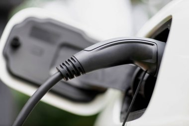 Kapalı elektrikli araç şarj noktasında alternatif temiz enerji şarj edilebilir EV araba tarafından geliştirilmiş çevresel otomotiv endüstrisi konsepti için şarj istasyonundan kabloya bağlandı