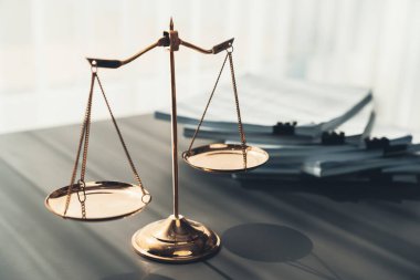 Parlak altın dengeli ölçek ve hukuk bürosundaki yasal kağıt yığını konsept adalet ve hukuki sembol olarak masanın üzerinde. Avukat ve avukatın adil ve eşitlik kararı için terazi uygulayın. denge