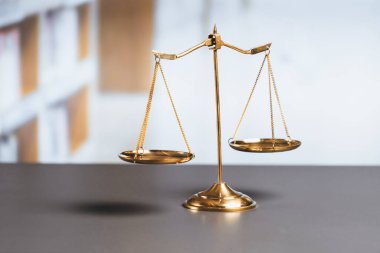 Mahkeme kütüphanesinin arka planında adalet ve adalet sembolü olarak parlak altın dengeli bir terazi. Avukat ve avukatın adil ve eşitlik kararı için terazi uygulayın. denge