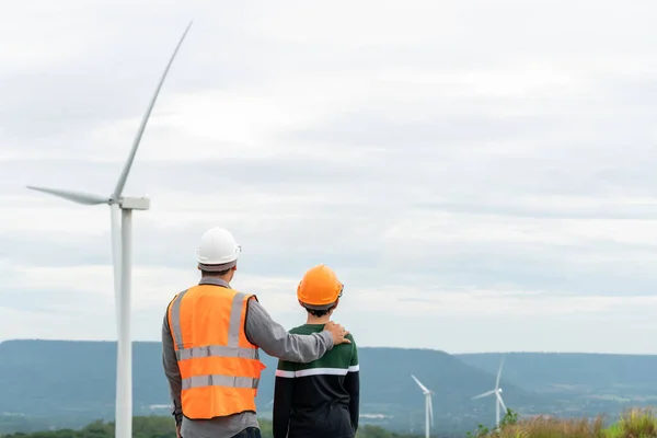 stock image Engineer with his son on a wind farm atop a hill or mountain in the rural. Progressive ideal for the future production of renewable, sustainable energy. Energy generation from wind turbine.