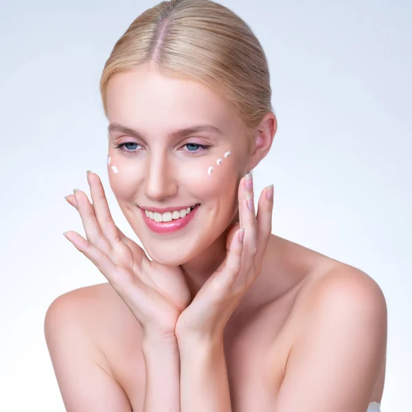 stock image Personable beautiful perfect clean skin soft makeup woman finger applying moisturizer cream on her face under contour eye for anti aging wrinkle. Facial skin rejuvenation in isolated background.