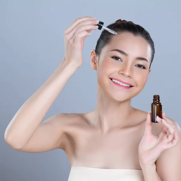 stock image Glamorous portrait of beautiful woman applying extracted cannabis oil bottle for skincare product. CBD oil dropper pipette for cosmetology treatment and cannabinoids concept in isolated background.