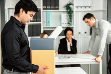 Depressed and disappointed employee packing his belongings after being fired for not being competent. Gossiped by his colleagues behind his back. Layoff due to economic depression.