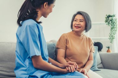 A contented senior woman visited by her personal caregiver and hold each others hands.