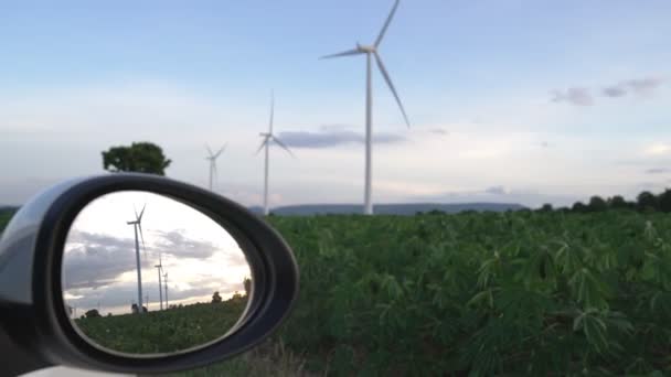 利用风力涡轮机的绿色和可再生能源在充电站充电的电动汽车侧面镜中反映出风力涡轮机的渐进式未来能源基础设施概念 — 图库视频影像