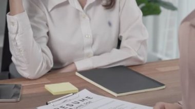 İş yerindeki profesyonel İK müdürüyle yakın çekim genç ve hevesli bir aday görüşmesi. Başvuru sahiplerini inceleyen işveren, iş görüşmesine hazırlanmak üzere işe devam ediyor.