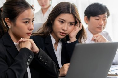 Focused businesspeople using laptop working on data analysis with serious facial expression in corporate environment at harmony office. Struggle in financial strategy planning at meeting desk.