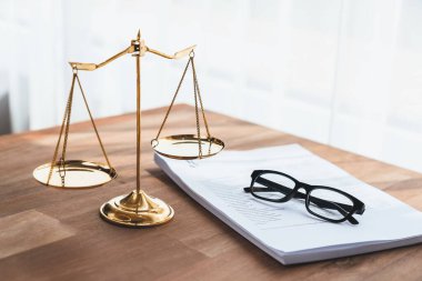 Parlak altın dengeli ölçek ve hukuk bürosundaki yasal kağıt yığını konsept adalet ve hukuki sembol olarak masanın üzerinde. Avukat ve avukatın adil ve eşitlik kararı için terazi uygulayın. denge