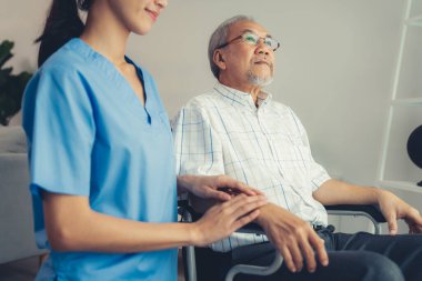 Caring nurse and a contented senior man in a wheel chair at home, nursing house. Medical for elderly patient, home care for pensioners.