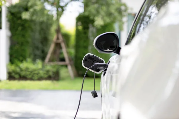 stock image Closeup electric vehicle plugged-in with cable from charging point powered for progressive concept by alternative clean energy rechargeable EV car at home charging station.