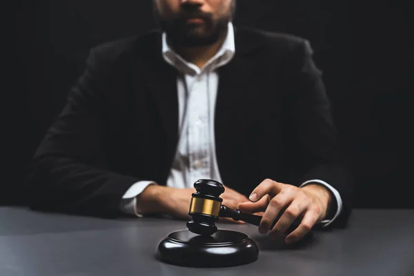 stock image Focus wooden gavel hammer with burred background of lawyer in black suit sit on his office desk, symbol of legal justice and integrity, balanced and ethical decision in court of law equility