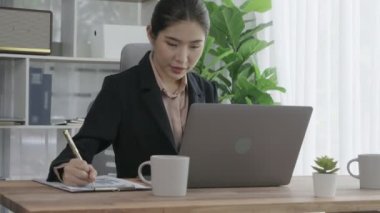 Ofiste çalışan ve dizüstü bilgisayar yazan hevesli bir iş kadını. Masasında oturmuş laptopla çalışan güzel bir ofis hanımı..