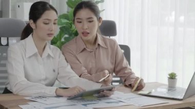 Ofis çalışma alanında birlikte çalışan iki genç hevesli iş kadını. Genç meslektaşlar tartışırken ve dizüstü bilgisayar kullanırken. Modern ofis çalışanları masada birlikte oturuyorlar..