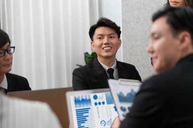 Harmony in office concept as business people analyzing dashboard paper together in workplace. Young colleagues give ideas at manager desk for discussion or strategy planning about project.