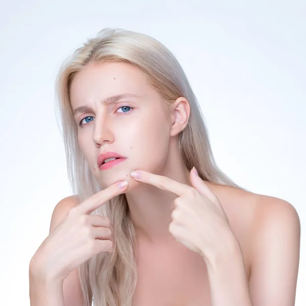 Acne problem troubling closeup personable worried woman with natural beauty skin checking her face squeezing pimple spots in isolated background. Copyspace for blemish skincare treatment problem.