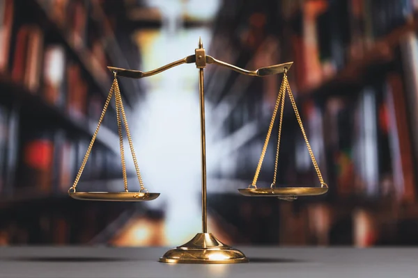 Shiny golden balanced scale in court library background as concept justice and fairness legal symbol. Scale balance for righteous and equality judgment by lawyer and attorney. equility