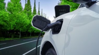 Elektrikli araç konsepti, yeşil çevre için yenilenebilir ve temiz enerjiyle çalışan EV otomobilinin varış noktasına ulaşmadan önce ormandaki şarj istasyonunun enerjisini şarj etmek için durur..