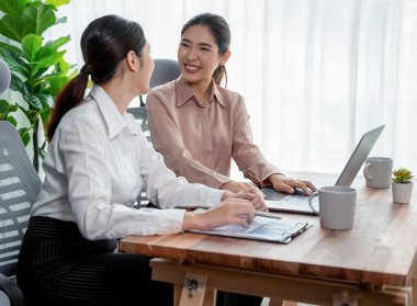 Modern ofis çalışma alanında iş birliği yapan iki genç ofis çalışanı, modern ofis çalışanı olarak profesyonelliklerini sergileyerek, dizüstü bilgisayarda tartışıyorlar ve birlikte çalışıyorlar. Coşkulu.