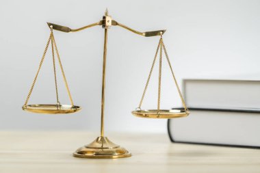 Hukuk fakültesinde adalet ve hukuki sembol olarak masanın üzerinde parlak altın dengeli bir terazi ve hukuk kitabı vardı. Avukat ve avukatın adil ve eşitlik kararı için terazi uygulayın. denge