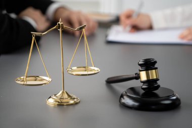 Hukuk bürosundaki masabaşında çalışan avukatın bulanık arka planına odaklan. Gavel, kanun koyucu ve avukatın adil ve eşit karar vermesi için çekiç. Eşitlik