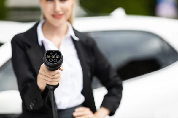 stock image Blur closeup businesswoman hand holding and pointing an EV plug at camera for electric vehicle as progressive idea of alternative sustainable clean and green energy for environmental concern.