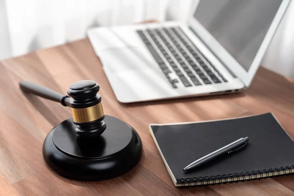 Closeup wooden gavel hammer with laptop and book and pen on desk on wooden office table background as justice legal system for lawyer and judge, Symbolize authority and fairness in trial. equility