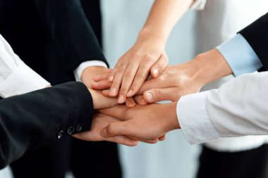 Top view closeup business team of suit-clad businesspeople join hand stack together. Colleague collaborate and work together to promote harmony and teamwork concept in office workplace.