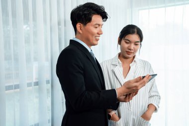 Manager advising guiding younger colleague with tablet in workplace. Couple businesspeople in formal wear working together on financial strategy as concept of teamwork and harmony in office.
