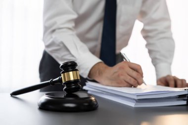 Hukuk bürosunun masasında yasal evraklarla çalışan avukatın bulanık arkaplanına odaklanın. Kanun yapıcı ve avukatın adil ve adil yargılaması için meşru çekiç. Eşitlik