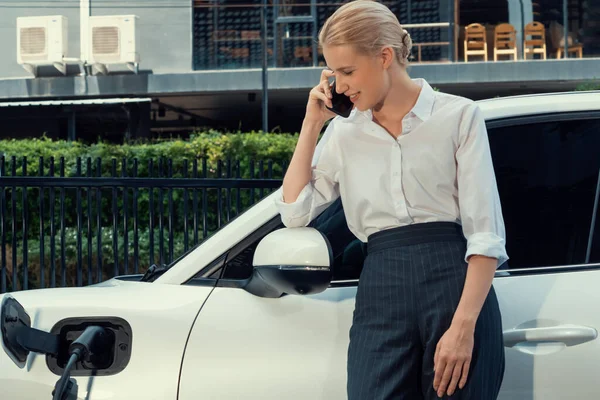 Closeup Progressive Businesswoman Talking Smartphone Leaning Electric Car Charging Station — Stockfoto
