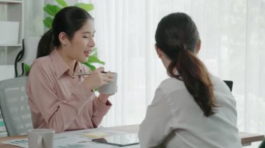 Ofis çalışma alanında birlikte çalışan iki genç hevesli iş kadını. Genç meslektaşlar tartışırken ve dizüstü bilgisayar kullanırken. Modern ofis çalışanları masada birlikte oturuyorlar..