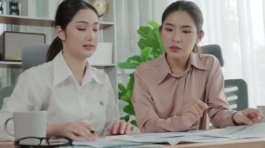 Ofis çalışma alanında birlikte çalışan iki genç hevesli iş kadını. Genç meslektaşlar tartışırken ve dizüstü bilgisayar kullanırken. Modern ofis çalışanları masada birlikte oturuyorlar..