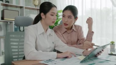 Ofis çalışma alanında birlikte çalışan iki genç hevesli iş kadını. Genç meslektaşlar tartışırken ve dizüstü bilgisayar kullanırken. Modern ofis çalışanları masada birlikte oturuyorlar..