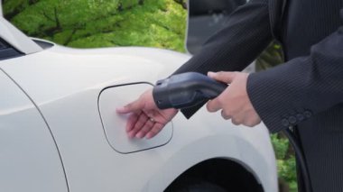 Çevre bilincini artırmak için sürdürülen ilerici kampanya, yeşil ormandaki şarj istasyonundan elektrik enerjisiyle çalışan elektrikli aracını şarj ediyor. Gelecekteki otomobiller için EV otomobil.