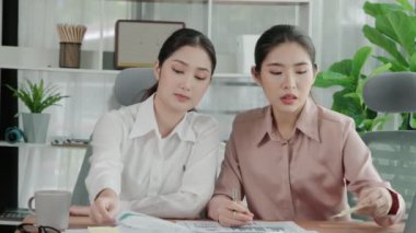 Ofis çalışma alanında birlikte çalışan iki genç hevesli iş kadını. Genç meslektaşlar tartışırken ve dizüstü bilgisayar kullanırken. Modern ofis çalışanları masada birlikte oturuyorlar..