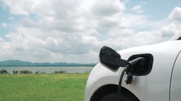 电动汽车概念的进步 电动汽车与充电站并存 可再生能源生态车绿地绿山绿地清洁环境的自然背景 — 图库视频影像