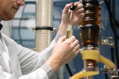 Bir bilim adamı ya da eczacı CBD kenevir yağını laboratuarda tıbbi amaçlar için çıkartıyor. Esrar çıkarma makinesinden üretilen alternatif esrar temelli ilaçlar.