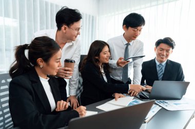 Harmony in office concept as business people analyzing dashboard paper together in workplace. Young colleagues give ideas at manager desk for discussion or strategy planning about project.