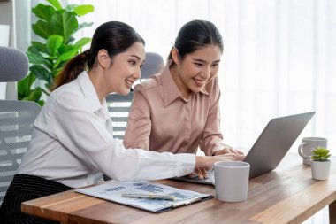 Modern ofis çalışma alanında iş birliği yapan iki genç ofis çalışanı, modern ofis çalışanı olarak profesyonelliklerini sergileyerek, dizüstü bilgisayarda tartışıyorlar ve birlikte çalışıyorlar. Coşkulu.