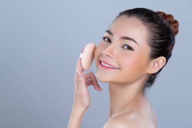 Glamorous beautiful female model applying cushion powder for facial makeup concept. Portrait of flawless perfect cosmetic skin woman put powder puff on her face in isolated background.