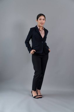 Kendine güvenen genç iş kadınının tüm vücut boyu resmi izole bir arka planda duruyor, resmi siyah takım elbise içinde poz veriyor. Ofisteki kadın ya da yönetici, zeki ve profesyonel görünümlü. Coşkulu.