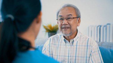 A young female doctor inquires about personal information of a contented senior at home. Medical care for the elderly, elderly illness, and nursing homes, home care.